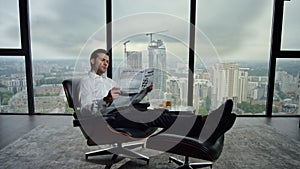 Businessman holding open newspaper in office. Worker reading financial newspaper