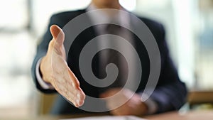 Businessman holding out his hand for handshake at work in office closeup