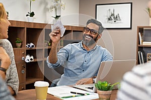 Businessman holding paper airplane at office