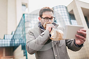 Businessman holding paper bag over mouth as if having a panic attack