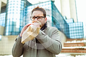 Businessman holding paper bag over mouth as if having a panic attack