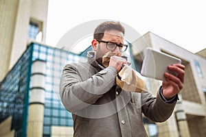 Businessman holding paper bag over mouth as if having a panic attack