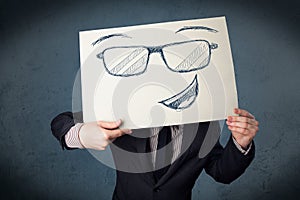 Businessman holding a paper with smiley face in front of his head