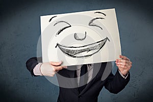 Businessman holding a paper with smiley face in front of his head