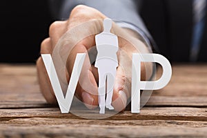 Businessman Holding Paperman Forming Vip Text On Table