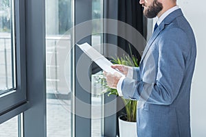 Businessman holding papers in hands in office