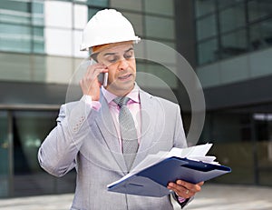 Businessman holding papers and having phone conversation