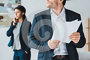 Businessman holding papers while woman talking on phone