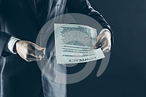 Closeup of a businessman holding a pen and a document with the terms of the contract.