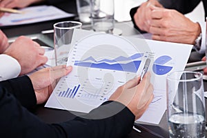 Businessman holding pen over graph in business meeting