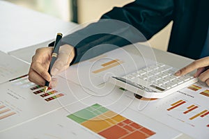 Businessman holding pen and paper pointing chart summary analysis calculating annual business report using laptop at desk in offic