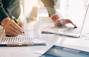 Businessman holding pen and pointing paper chart summary analyzing annual business report with using laptop at room office desk.