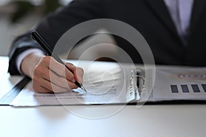 Businessman holding pen and signing on business document.