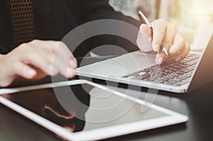 Businessman holding pen typing keyboard computer laptop and tablet on desk. Business technology digital internet work job research