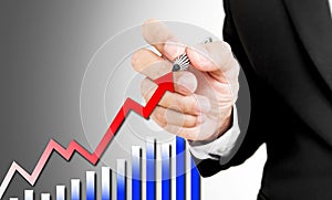 Businessman holding pen writing rising arrow and bar graph