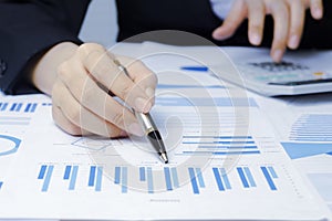 Businessman holding a profitability statistics analysis pen from a graph document in hand  to plan profit