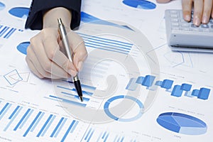 Businessman holding a profitability statistics analysis pen from a graph document in hand  to plan profit