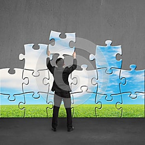 Businessman holding puzzles to assembly on concrete wall