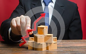 Businessman holding a red arrow up over boxes. Increase sales rate, industrial goods production volumes growth , expanding export