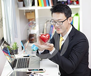 Businessman holding red heart in office. The concept of work by heart photo