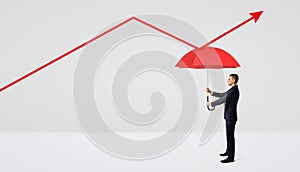 A businessman holding a red open umbrella right under a red statistic arrow pointing upwards.