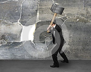 Businessman holding sedgehammer to crack wall