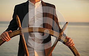 Businessman holding ship wheel and navigates