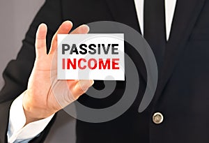 Businessman holding or showing card with text passive income