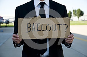 Businessman holding a sign that says bailout?