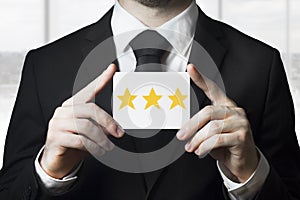 Businessman holding sign three golden rating stars