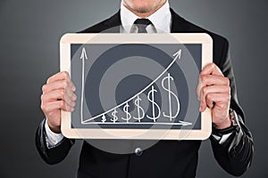 Businessman Holding Slate With Graph And Dollar Signs