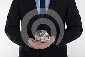 Businessman holding small house in hands. Insurance and security