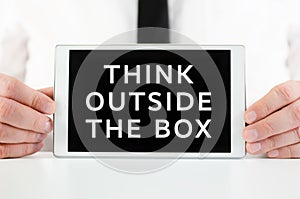 Businessman holding a smart tablet with sign Think outside the box written on screen