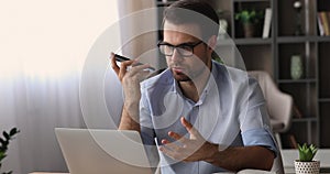 Businessman holding smartphone communicates to colleague on speakerphone