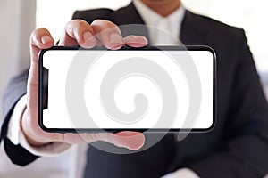 Businessman holding smartphone forward empty white screen for your text or picture.