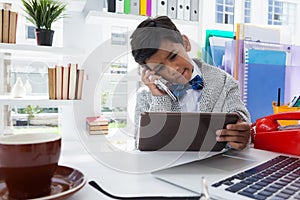 Businessman holding tablet computer while talking on smartphone