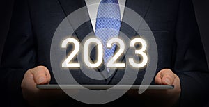 A businessman holding a tablet PC and 2023. New year business concept