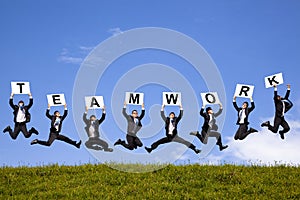 Businessman holding teamwork text and jumping