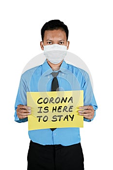 Businessman holding text of Corona is here to stay