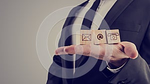 Businessman holding three wooden cubes with contact symbols