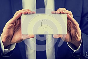 Businessman holding two interlocked puzzle pieces photo