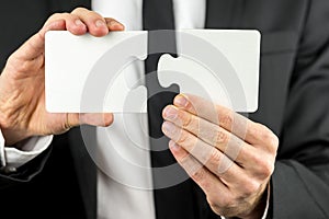 Businessman holding two pieces of a blank puzzle