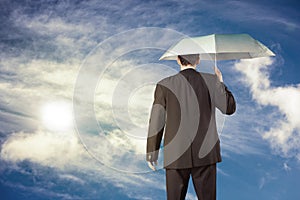 Businessman holding umbrella at sunny day