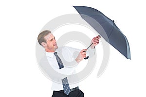 Businessman holding umbrella to protect himself