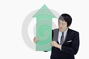 Businessman holding up an arrow, pointing upwards