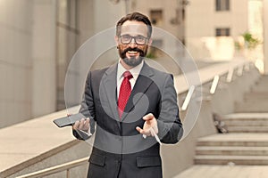 A businessman holding up credit card and making online payment on his cellphone with building background. happy businessman