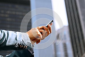 Businessman holding and using the mobile smart phone outside