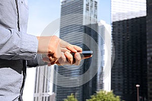 Businessman holding and using the mobile smart phone outside