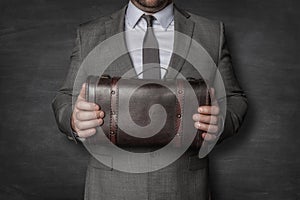 Businessman holding vintage suitcase in front of him