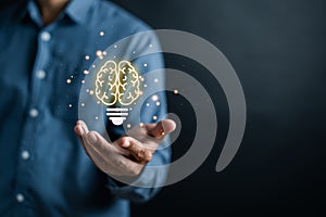 Businessman holding virtual lightbulb with brain icon, idea, innovation and inspiration with glowing virtual brain, smart